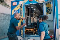 Paramedics load a patient into an ambulance in a rapid response scenario outdoors.